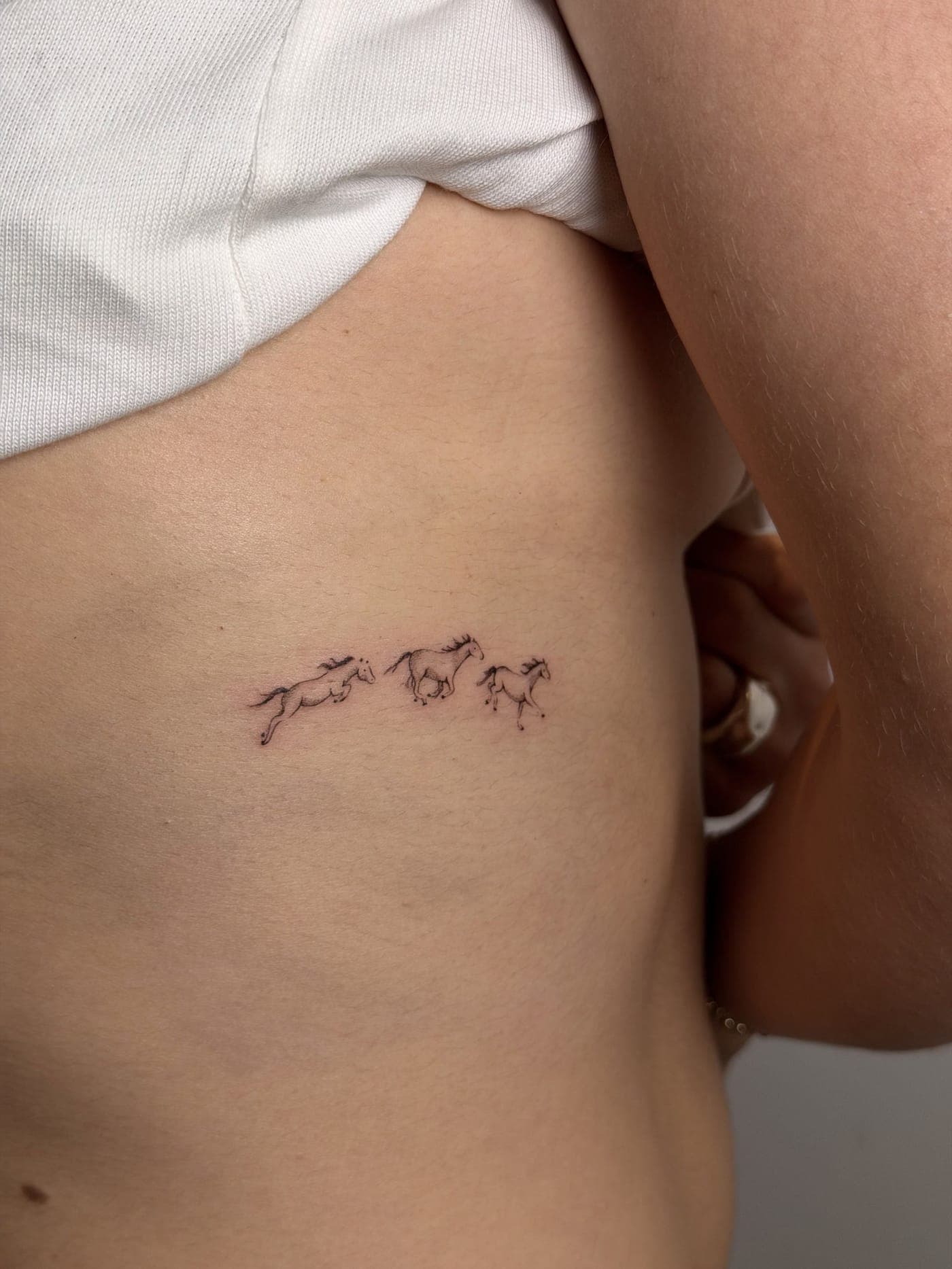 Tatuaje fine line — Caballitos en las costillas